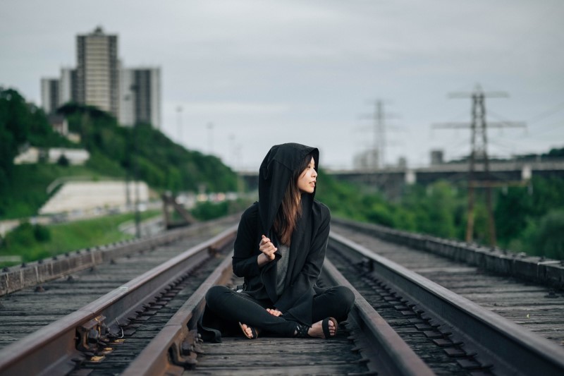 Woman sitting on railroad tracks