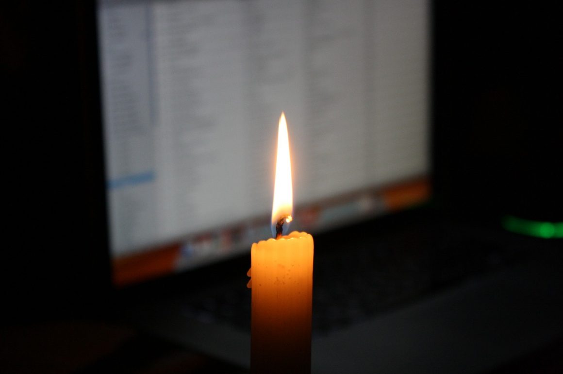 low-tech candle before a high-tech computer