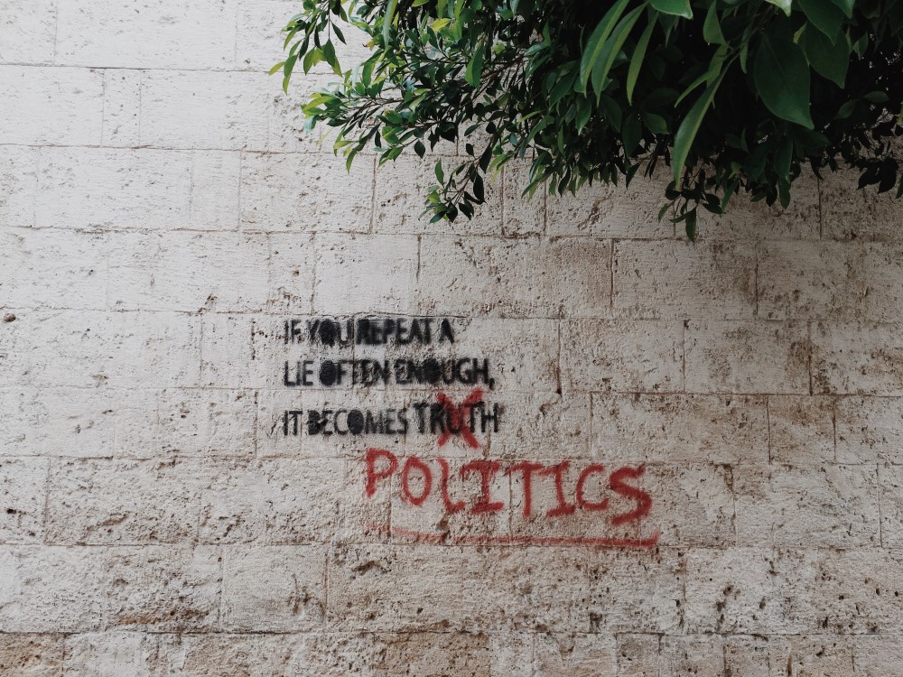 Graffiti on a wall that says If you repeat a lie often enough, it becomes politics
