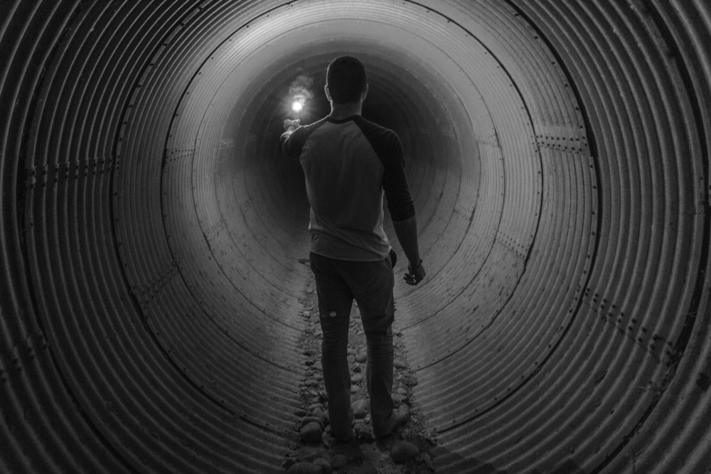 man in dark tunnel holding a light