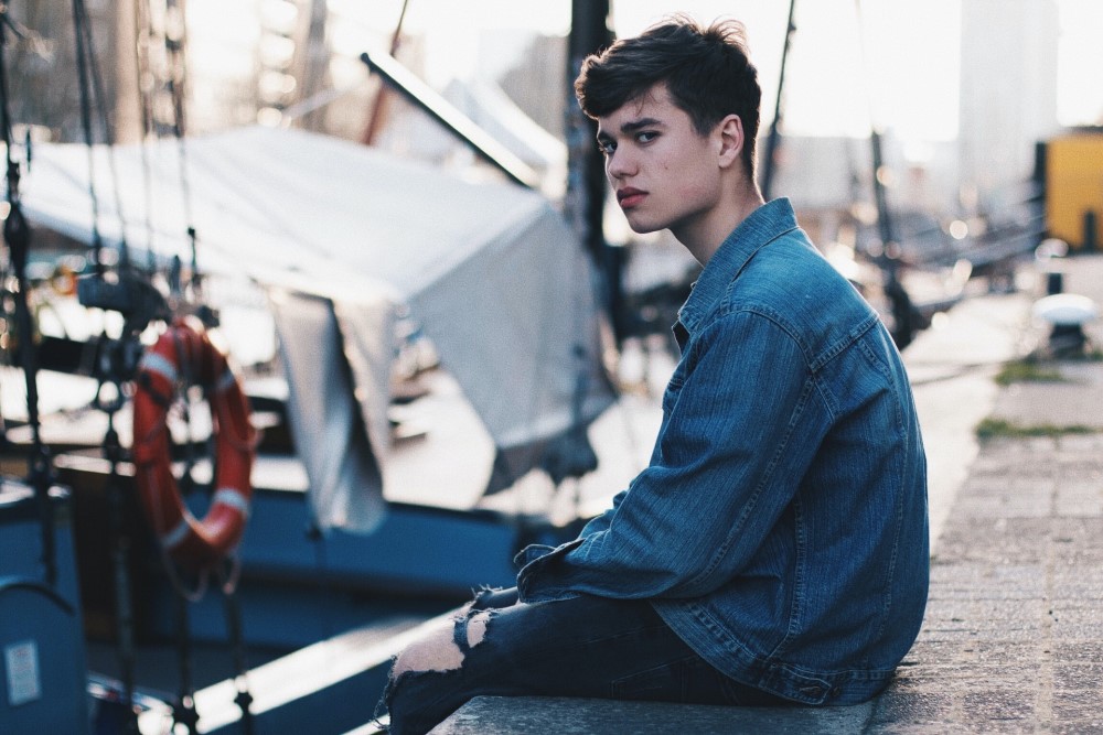 boy sitting near docked boats