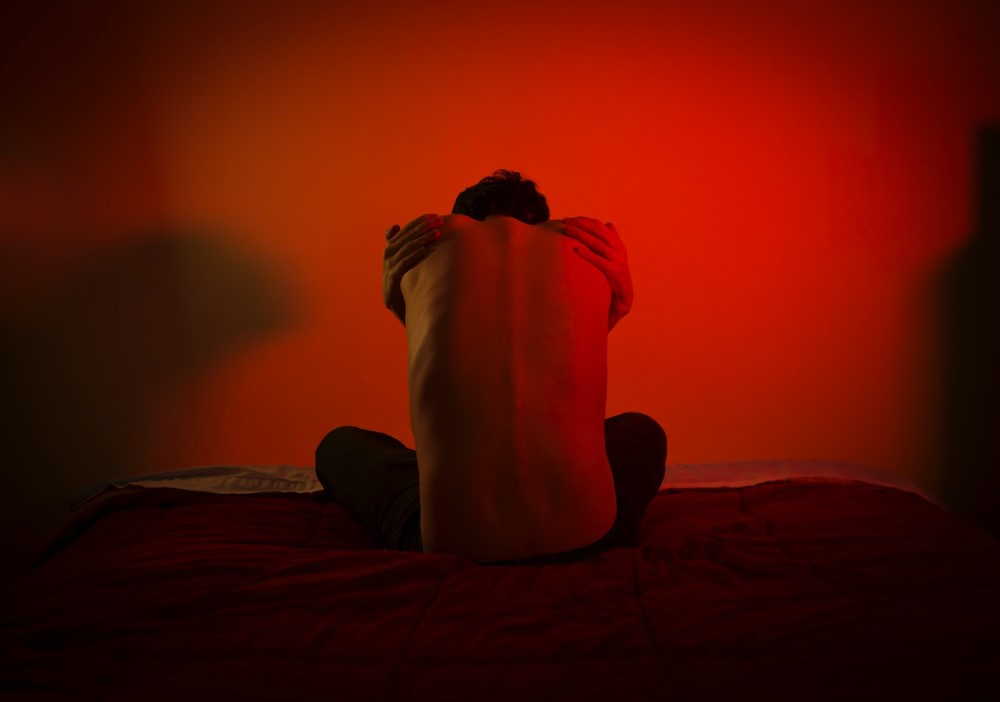 man holding his back with red background