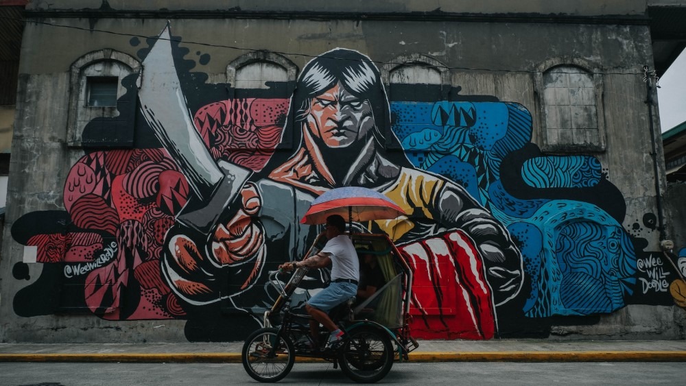 mural of guy with sword in Manila Philippines with man on tricycle